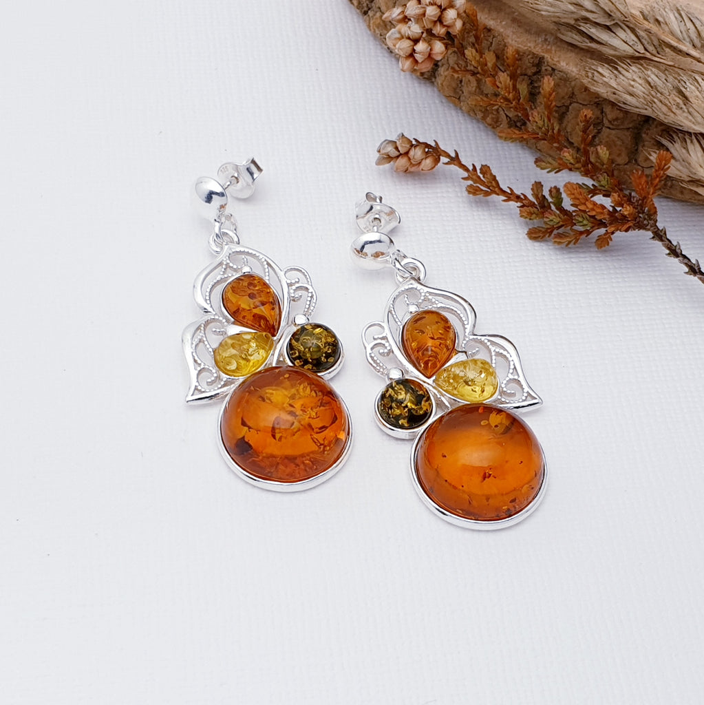 Each earring features a large Toffee Amber round stone in a simple setting, followed by one round green stone and two teardrop, toffee and yellow Amber Stones. A Sterling Silver butterfly cut out design showcases the stones beautifully. This fabulous nature inspired design uses the finest Baltic amber. The Sterling Silver stud fixing makes these earrings extra secure so you won't need to worry about loosing them. 