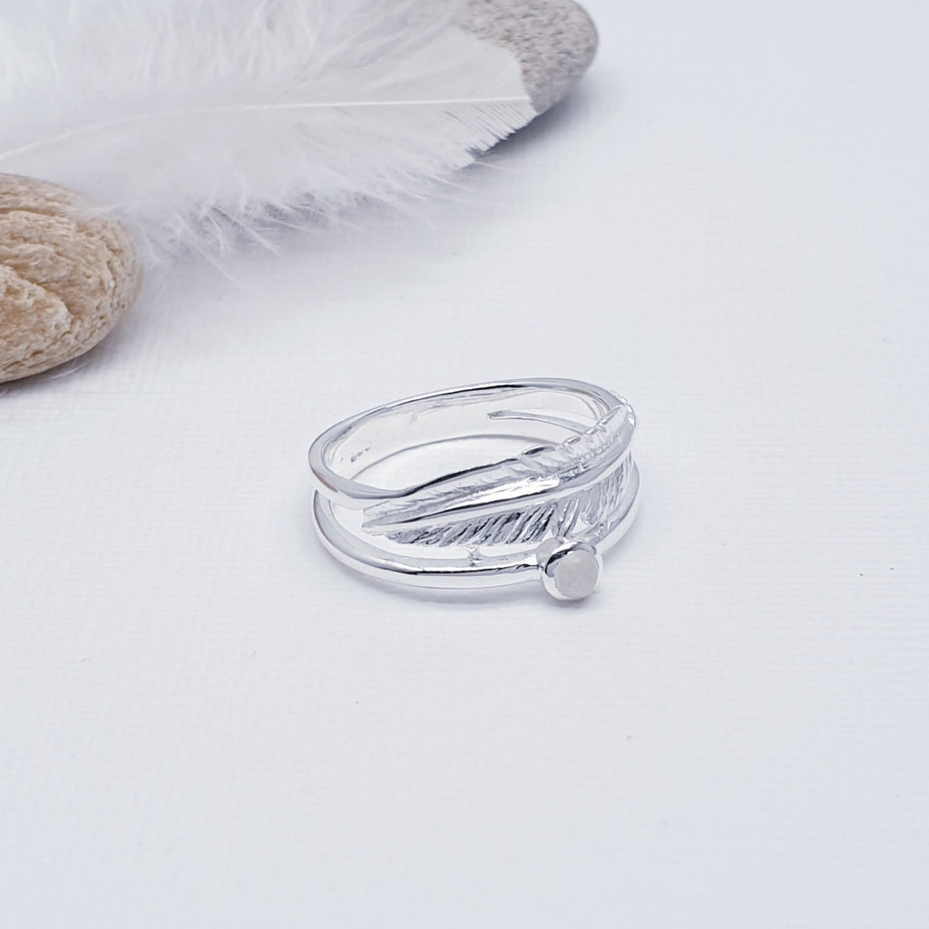 A beautiful design, this ring features a stunning cabochon, round, Moonstone stone in a simple setting. Above the stone is a gorgeous feather, with an 'icing sugar' finish and gorgeous detailing. Two silver bands are fused together at both ends creating an interesting design.