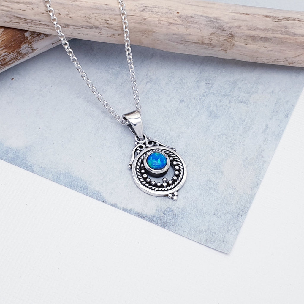 A gorgeous design, this pendant features a round, cabochon Reconstituted Opal stone in a simple setting. Intricate Sterling Silver detailing decorates around the stone, and is given depth and presence by the clever use of oxidisation. 