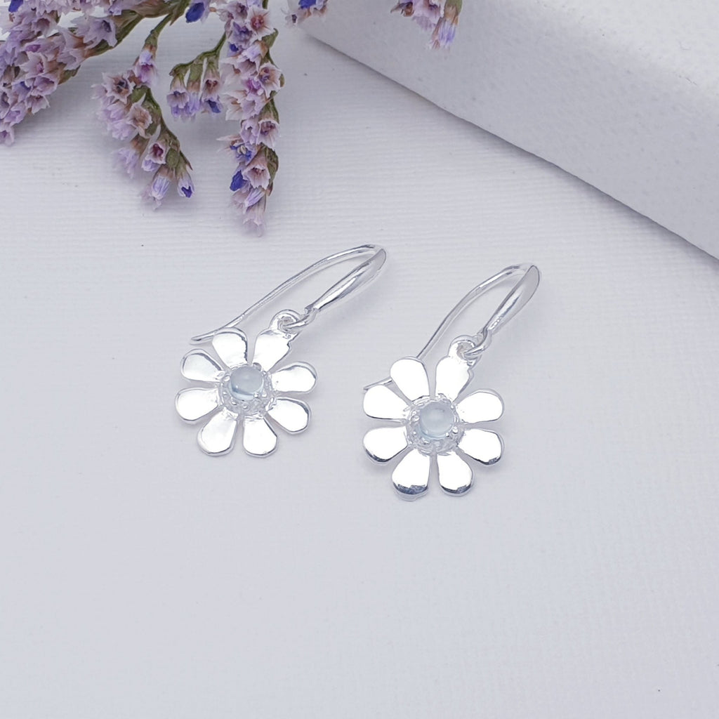 A dainty design, each earring features a round cabochon Blue Topaz stone. The Blue Topaz stones are highlighted by decorative Silver petals creating a detailed daisy. These earrings will add sparkle and shine to any outfit, you just can't go wrong with this understated pair of studs. 