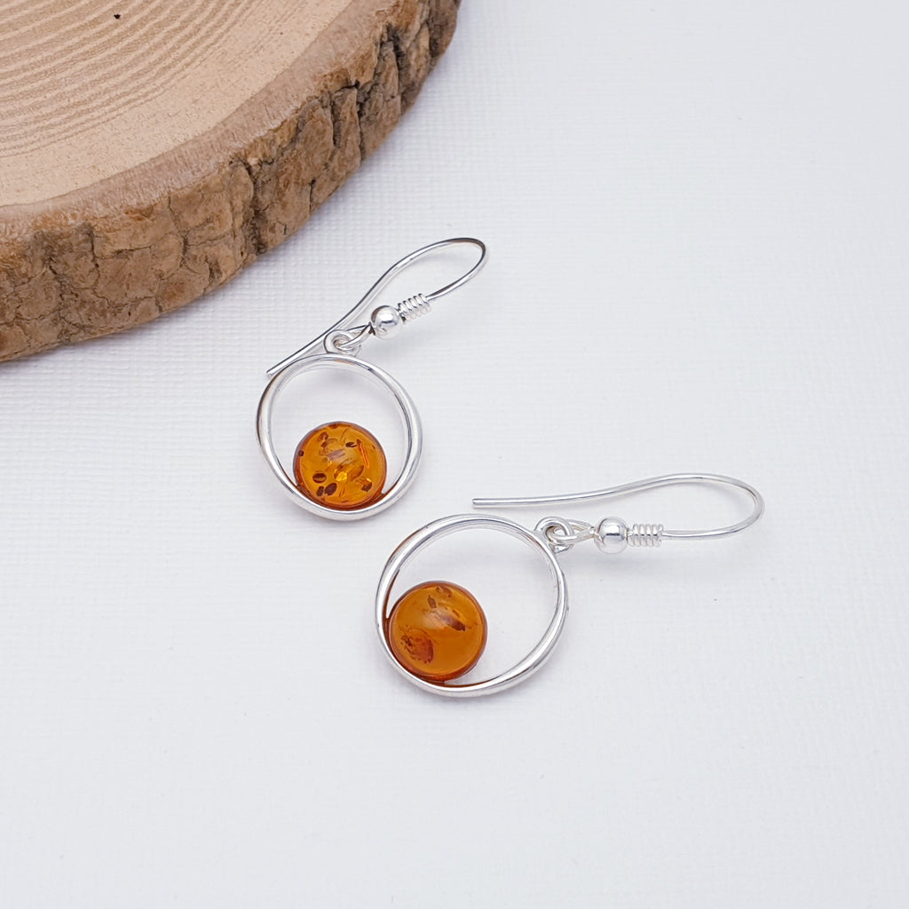 Each earring features a round Baltic Amber stone. A Sterling Silver oval design showcases the stone beautifully. Light on the ear and easy to wear, these earrings are ultra feminine and are bound to become a very well loved pair of everyday earrings.