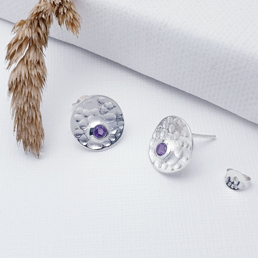 Our Sterling Silver Amethyst Hammered Disk Studs are perfect for every day wear.  Sometimes less is more, and that is definitely the case with this gorgeous pair of Amethyst studs. These stunning studs feature small, cabochon Amethyst's sitting off-center on beautiful, hammered Sterling Silver disks.