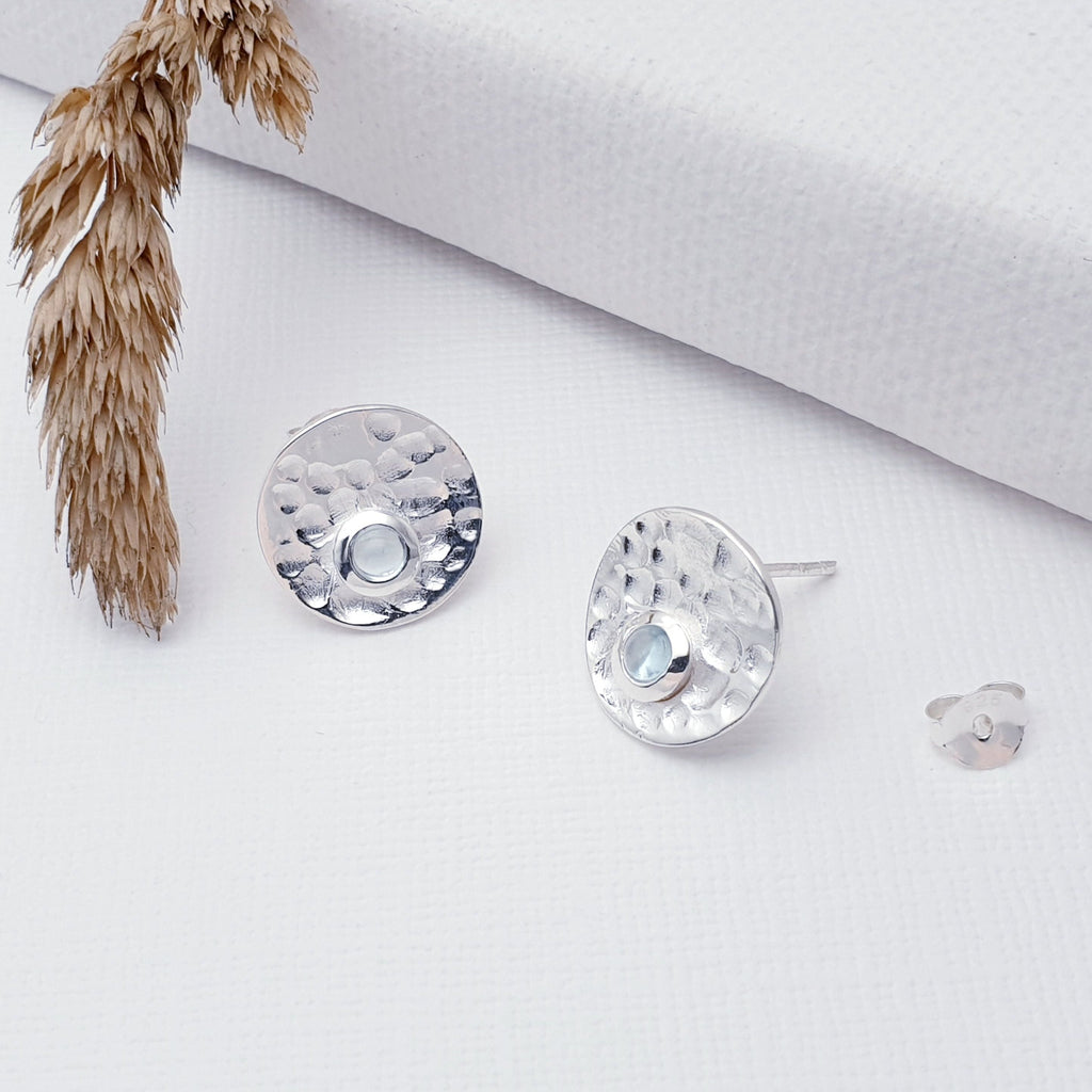Our Sterling Silver Blue Topaz Hammered Disk Studs are perfect for every day wear.  Sometimes less is more, and that is definitely the case with this gorgeous pair of Blue Topaz studs. These stunning studs feature small, cabochon Blue Topaz' sitting off-center on beautiful, hammered Sterling Silver disks. 