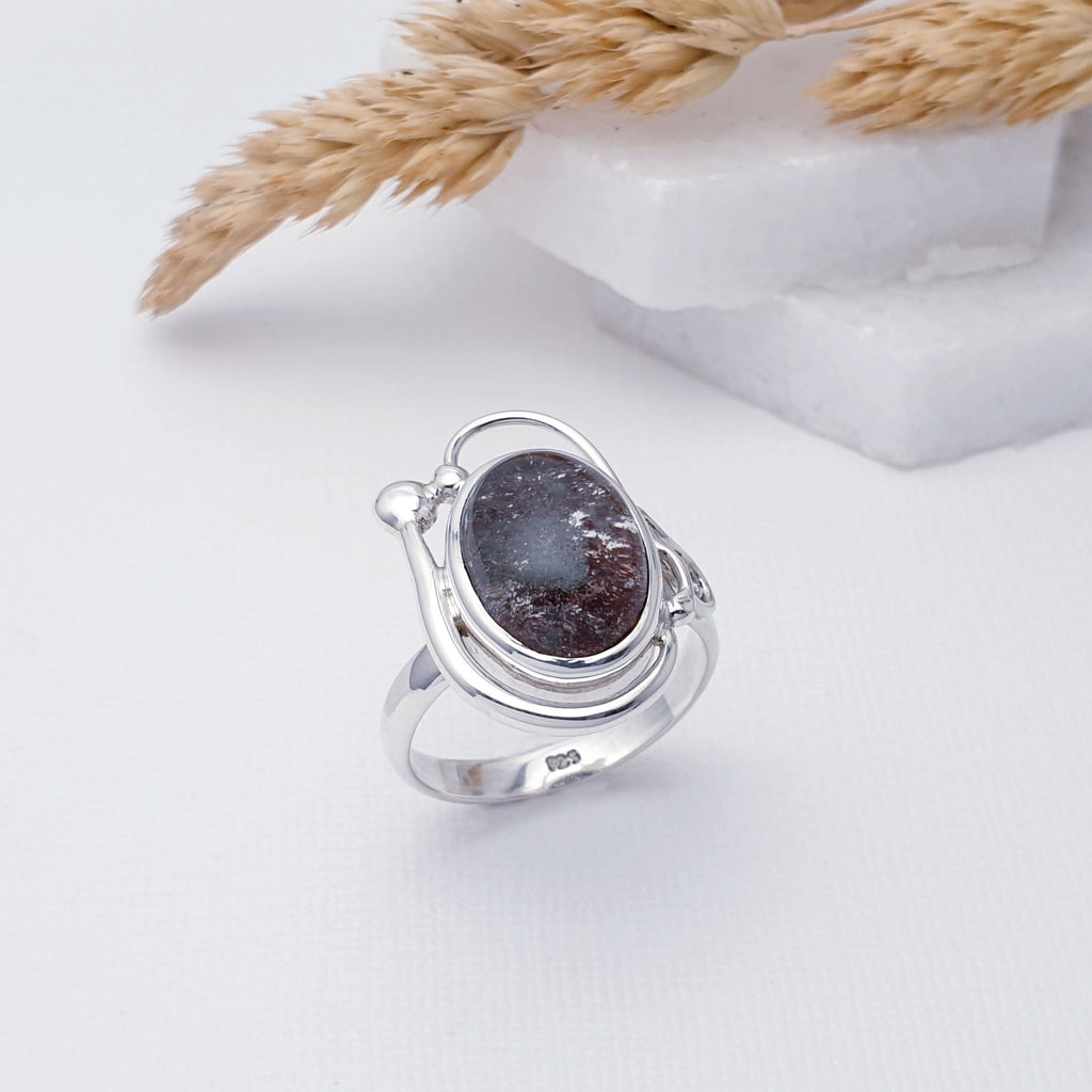 Our Lodolite Asteria Ring is a stunning design and is perfect for everyday wear or special occasions.  This ring features an oval, cabochon, Lodolite stone in a simple setting. Up one side of the Lodolite stone, our Silversmiths have added an elegant Sterling Silver swirl that is finished off with a Silver ball. On the other side, finer Silver swirls, complete this gorgeous design.
