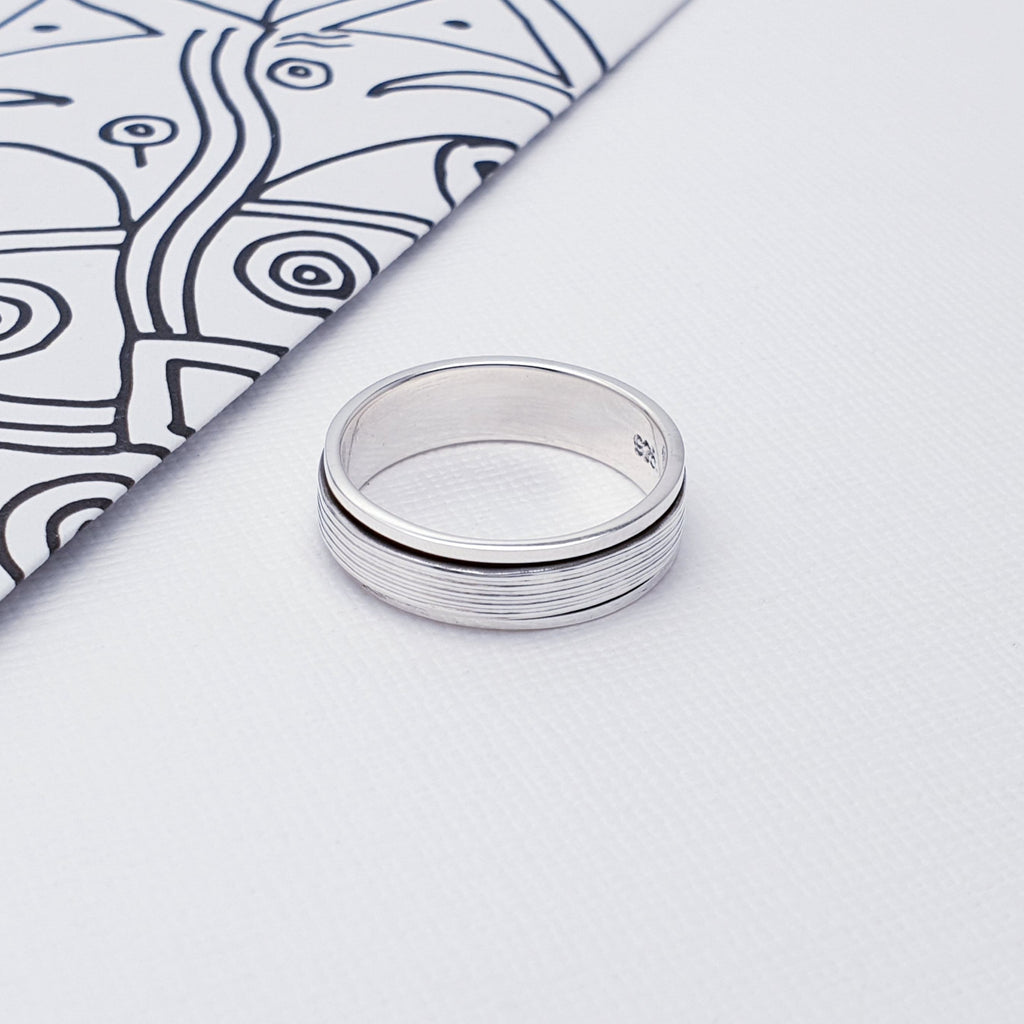 Our Silver Unisex Spinner Ring is perfect for everyday wear.  This stress reliever ring features two band rings, with a ridged band ring rotating on the inner band ring, and an oxidised finish. Perfect for people who love to fiddle and just can't keep their hands still, the simple repetitive motion of the Sterling Silver band spinning smoothly inspires inner peace.