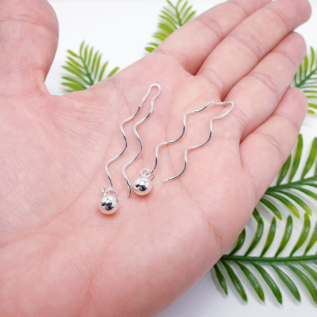 a pair of Sterling Silver Twisted Ball Pull Through Earrings inn the palm of a hand