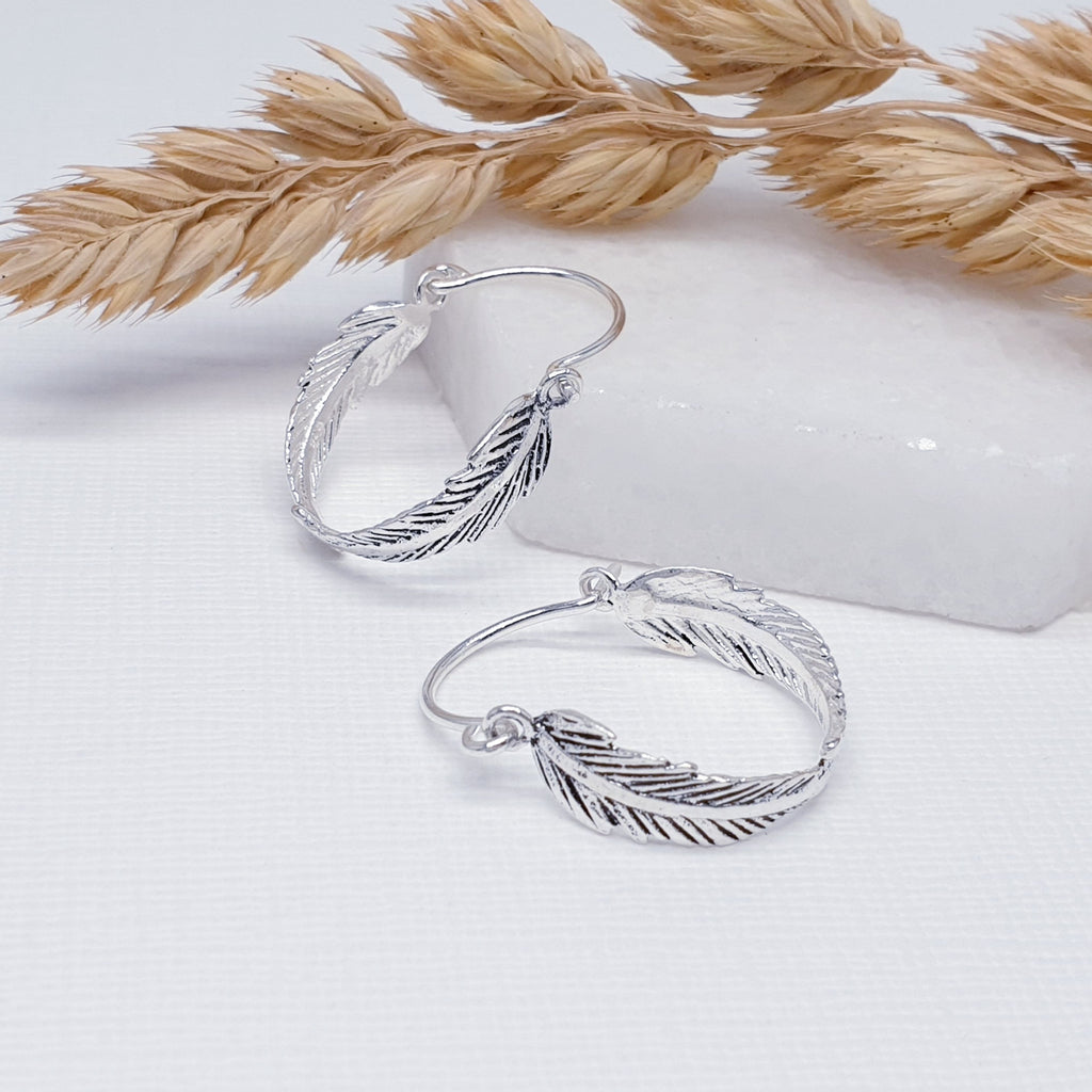 a pair of small sterling silver feather hoops