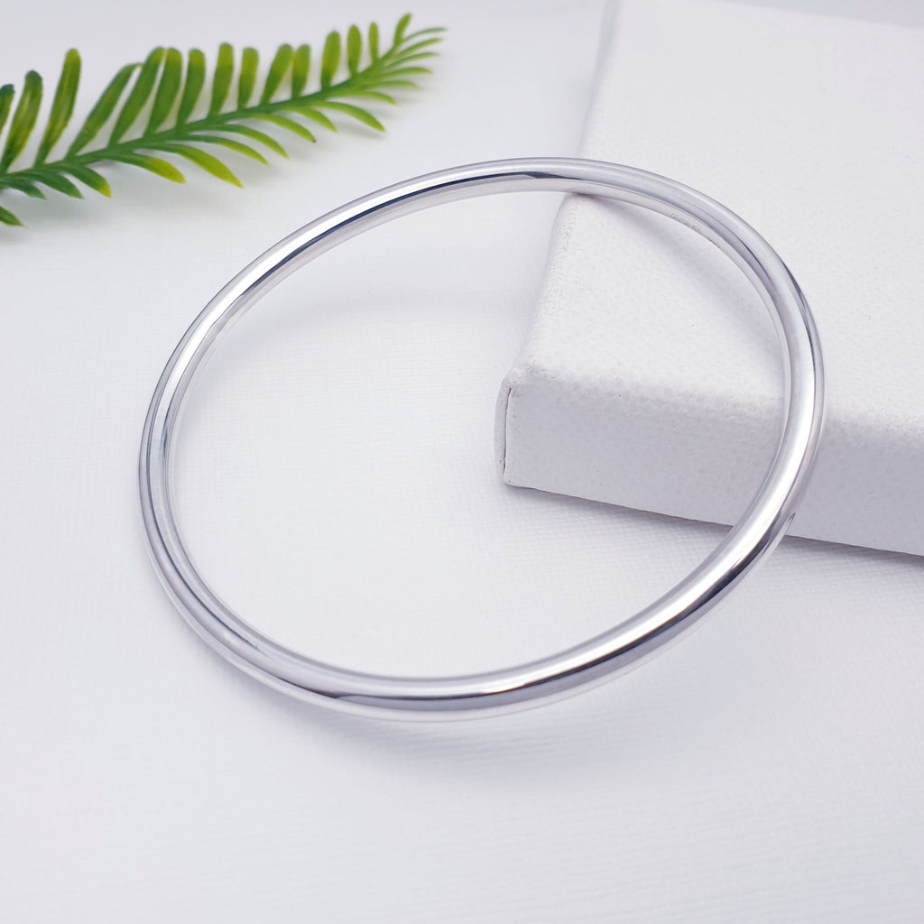 simple sterling silver round band bangle with foliage background