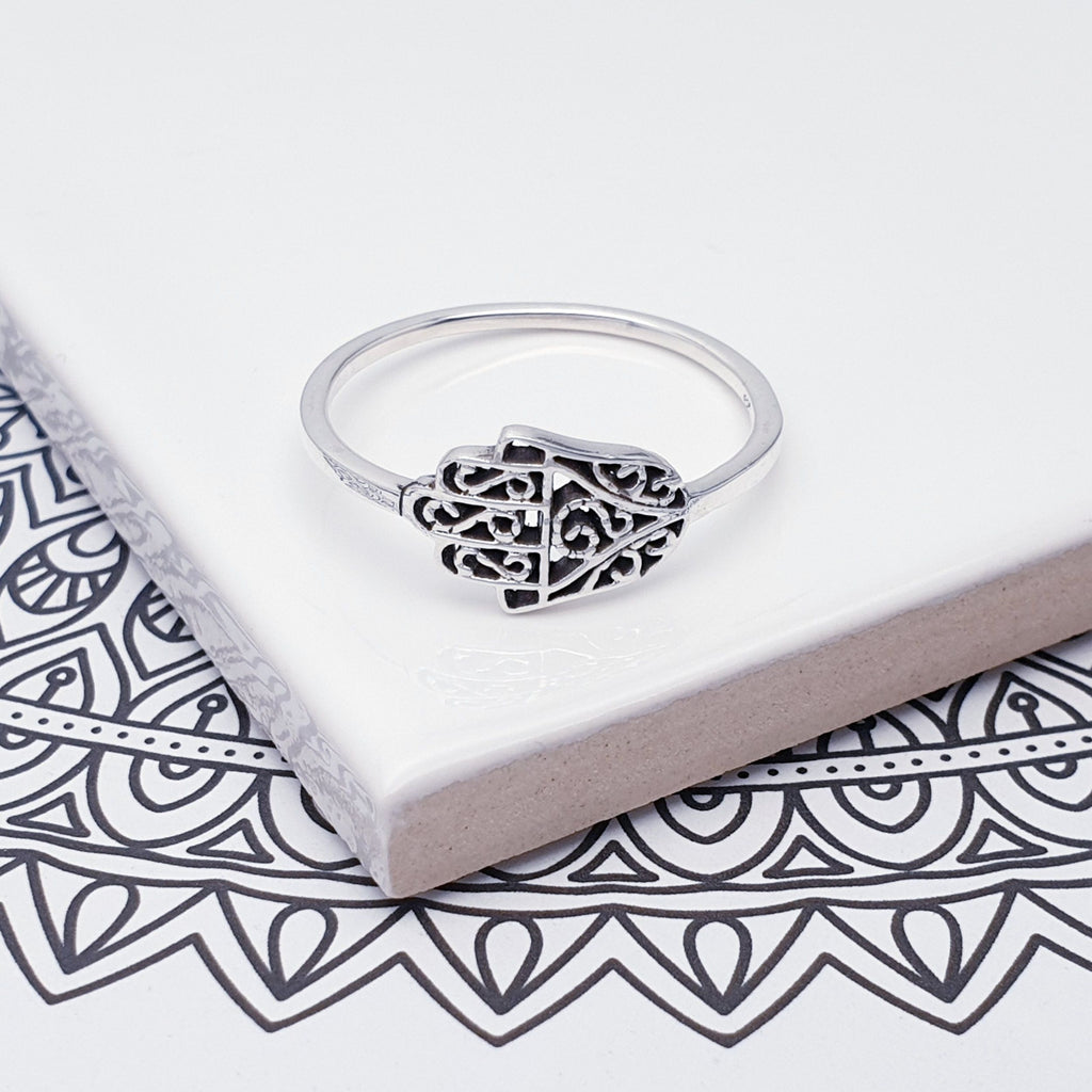 A Sterling Silver Hamsa hand Ring on top of patterned canvas