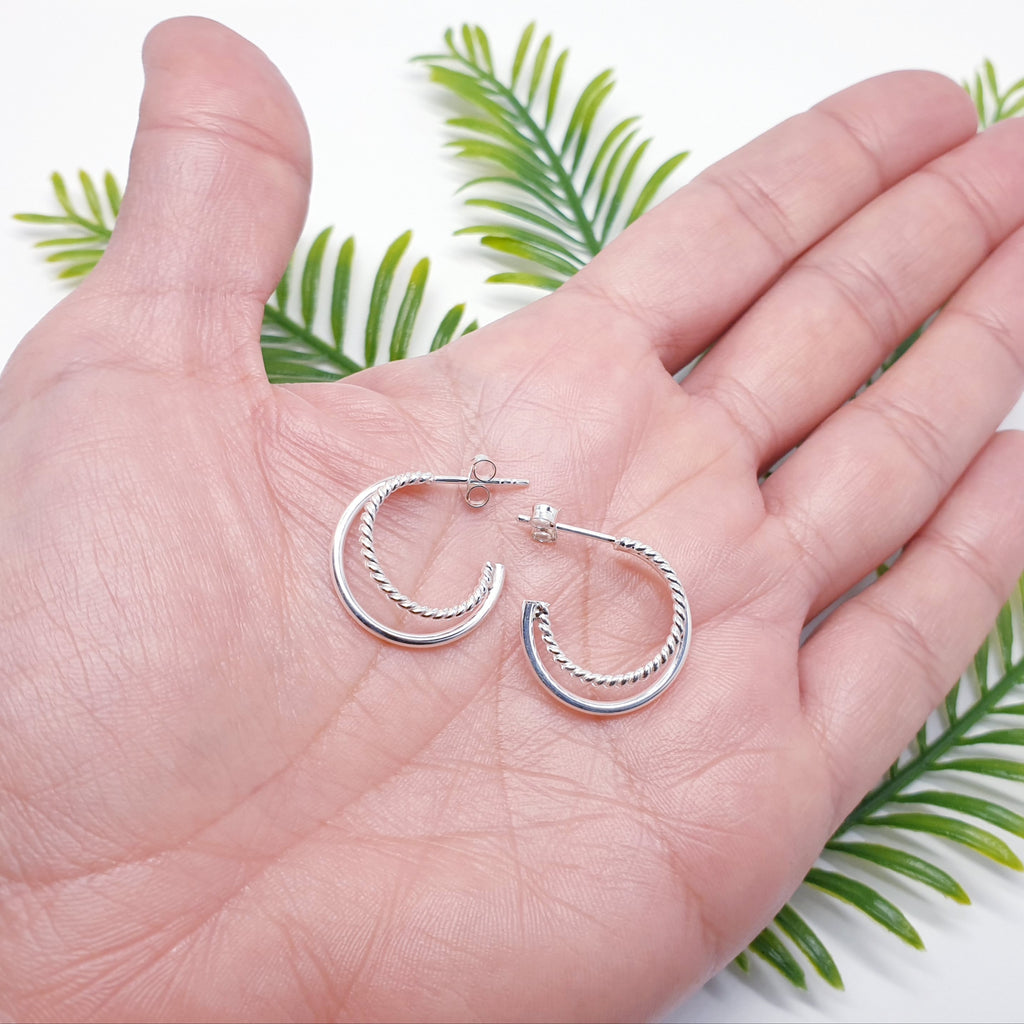 sterling silver rope design half hoops in the palm of a hand