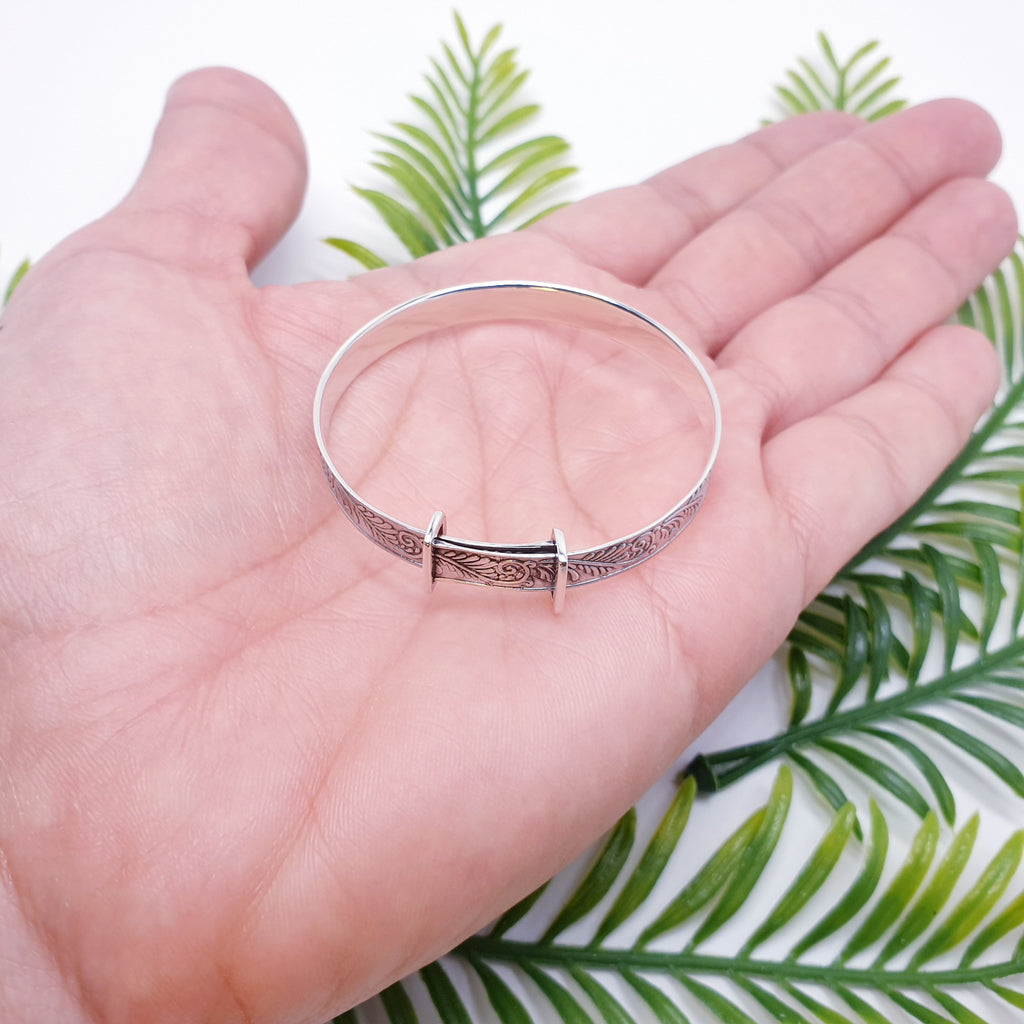 sterling silver Baby christening bangle with botanical fern design in palm of hand