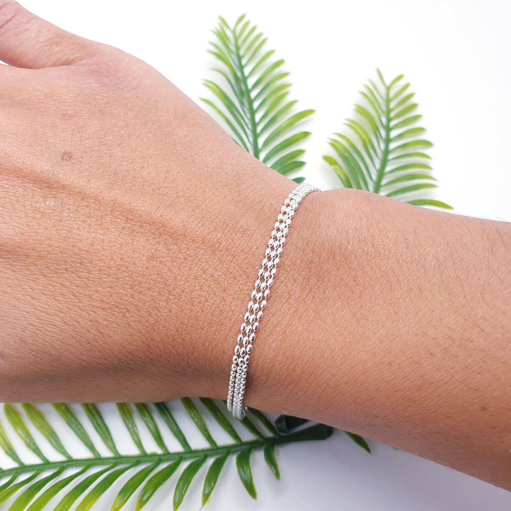 Delicate, adjustable sterling silver bracelet with three strands of tiny oval beads on a fine chain.