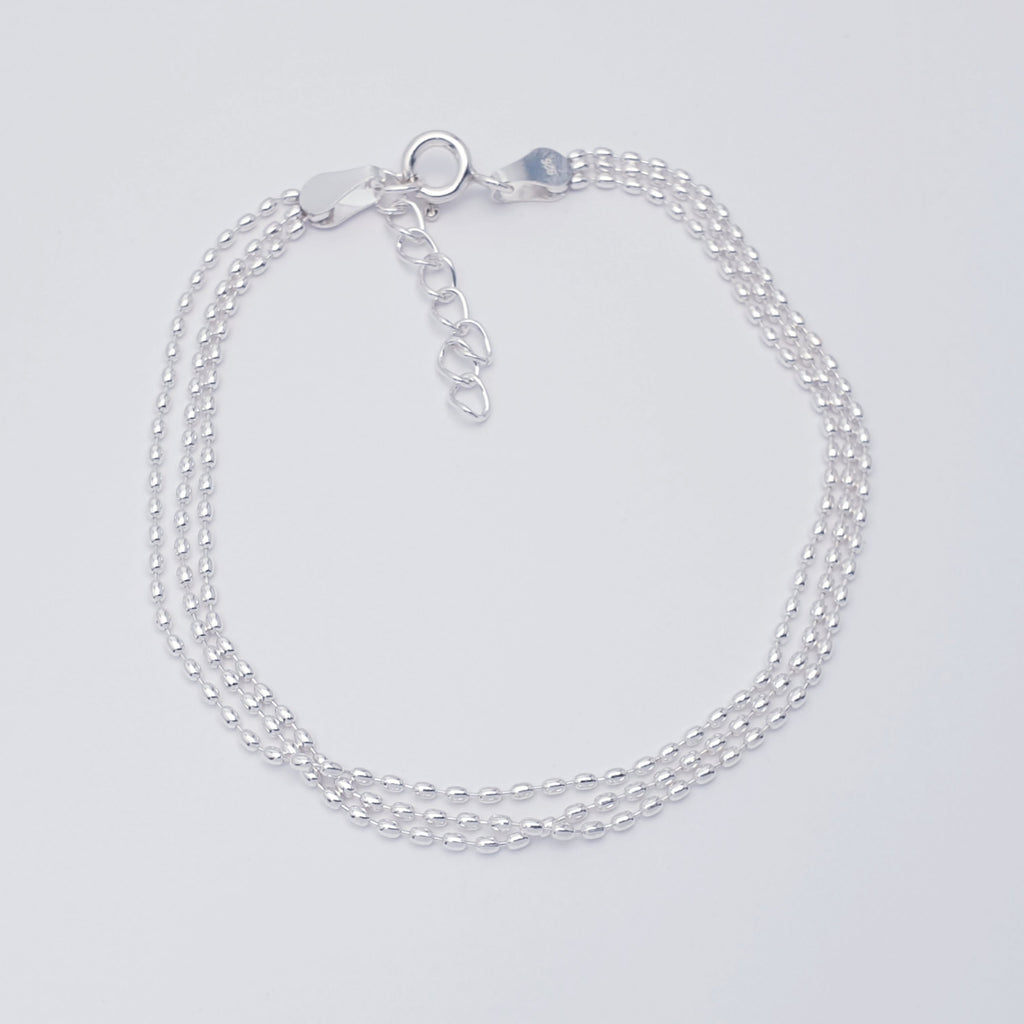 Delicate, adjustable sterling silver bracelet with three strands of tiny oval beads on a fine chain.