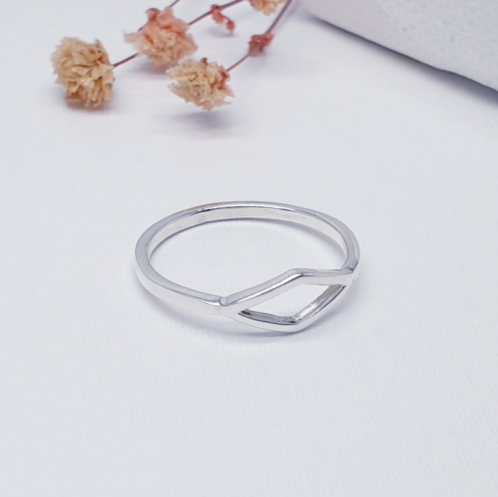 Handmade sterling silver rhombus, diamond shape ring, displayed on a white background with pink flowers as decoation