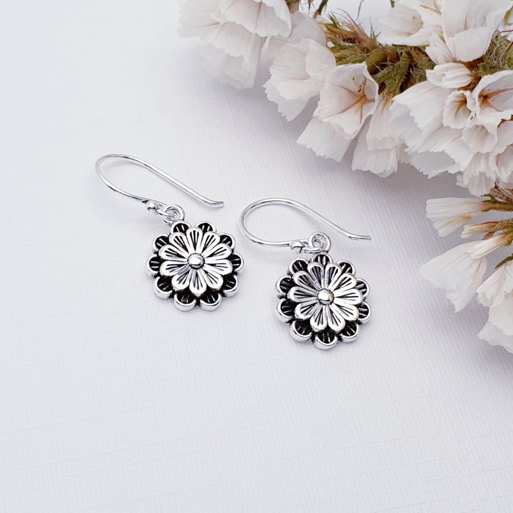 Multi petal flower hook earrings. Photographed on a white background with white flowers in the corner.