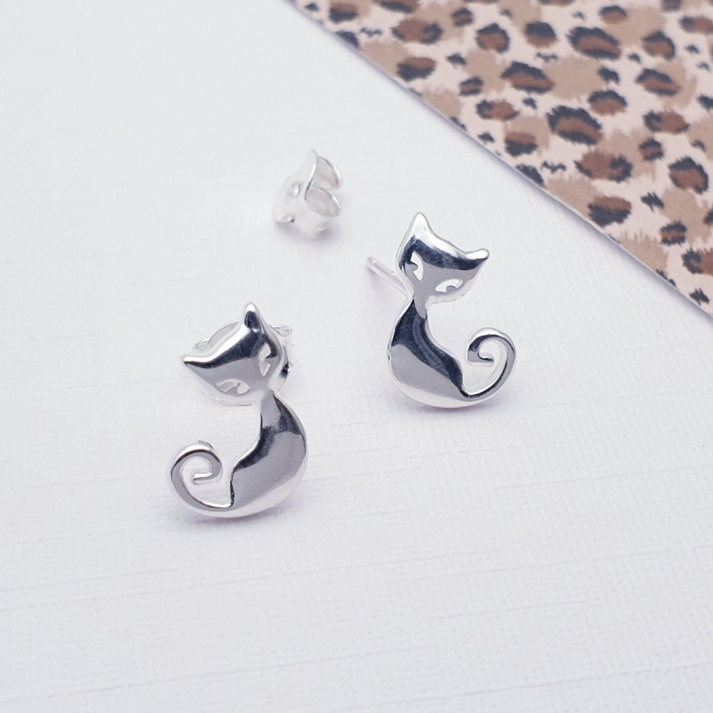 Silver cat studs on a white background with cheetah print fabric in the top right corner