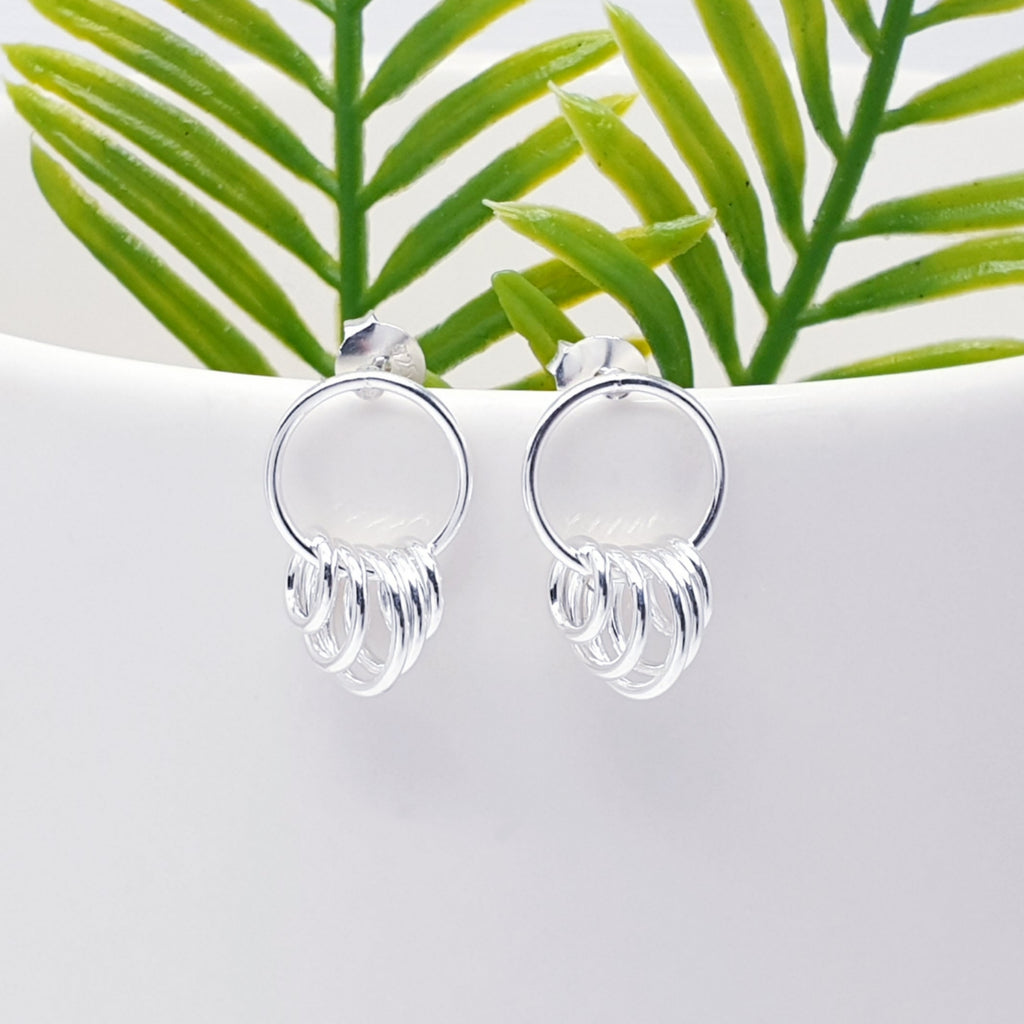 Sterling Silver Multi Link Stud Earrings on the edge of a white plant pot with green plants behind them