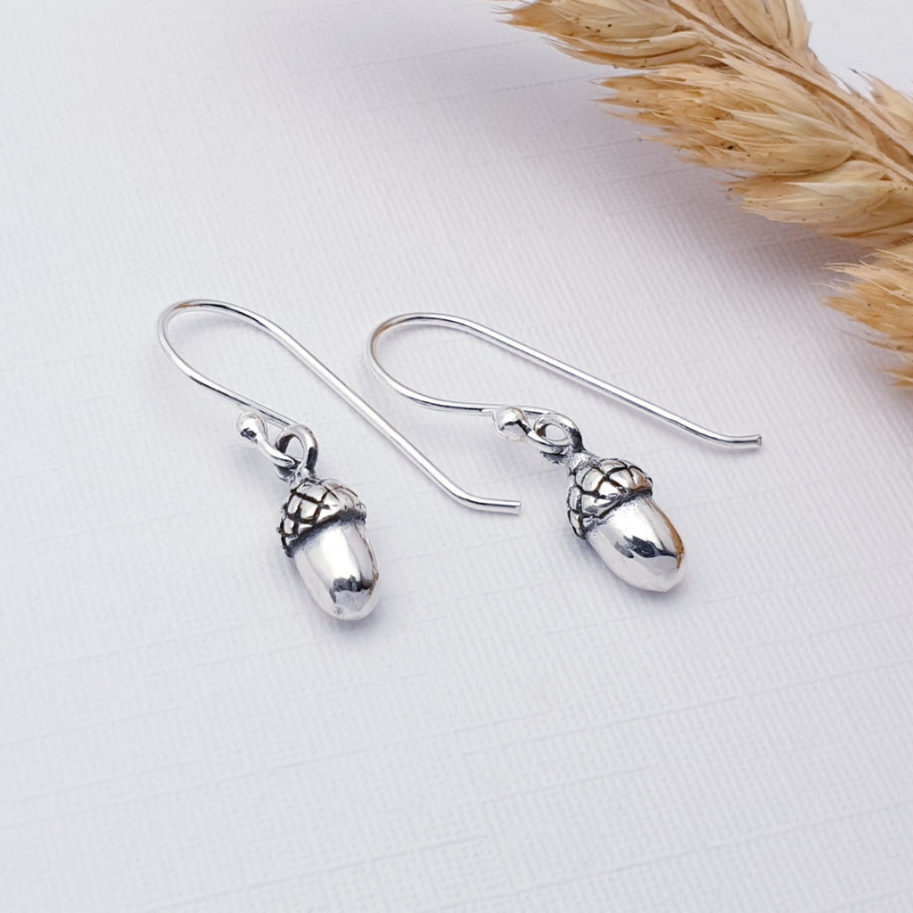 Sterling Silver Acorn Earrings on a white background with wheat in the top right corner