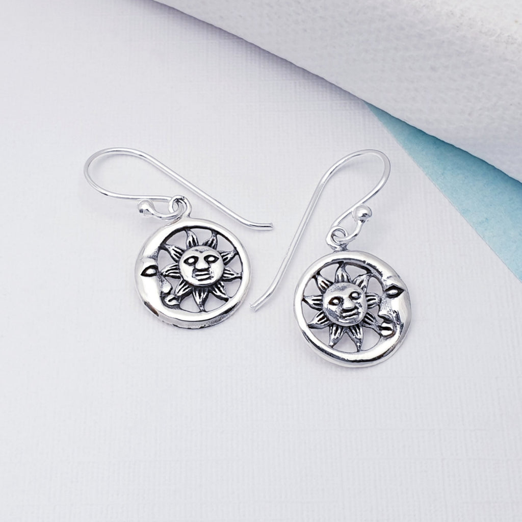 Sun and Moon earrings on a white background with a pop of blue card on the right hand side