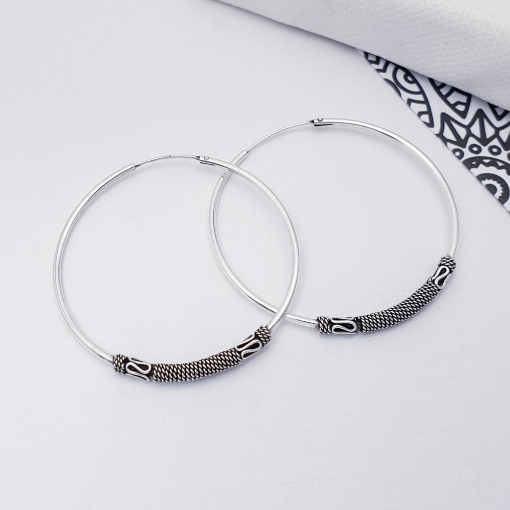 Our sterling silver indo 4.5 cm hoops displayed on a white background with back and white pattern as decorations