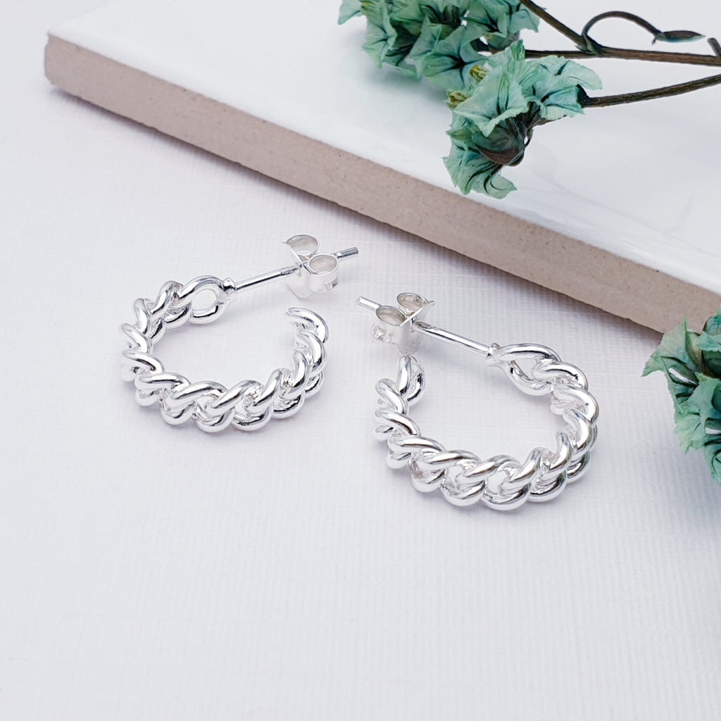 Sterling Silver Curb Tight Link Half Hoops on a white background with green flowers in the top right corner