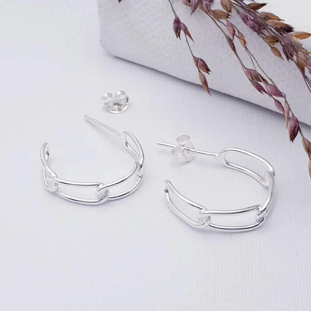 Sterling Silver Curb Link Half Hoops on a white background with purple filigree in the top right corner