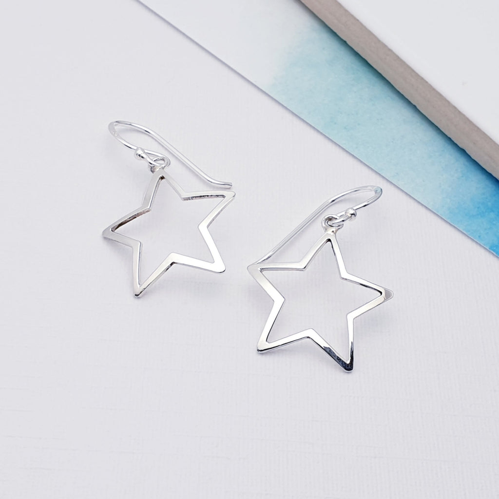 Sterling Silver Open Star Earrings on a white background with blue card in the top right corner