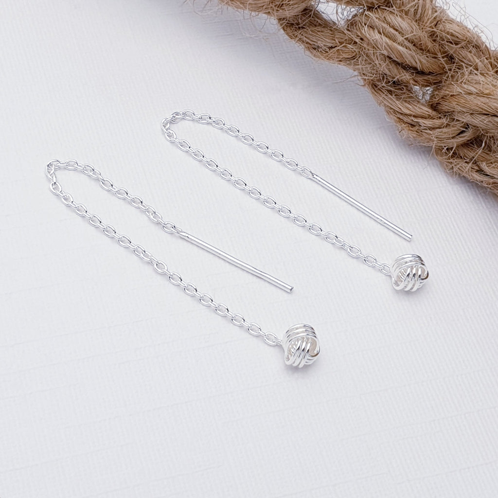 Sterling Silver Knot Pull Through Earrings on a white background with rope in the top right corner