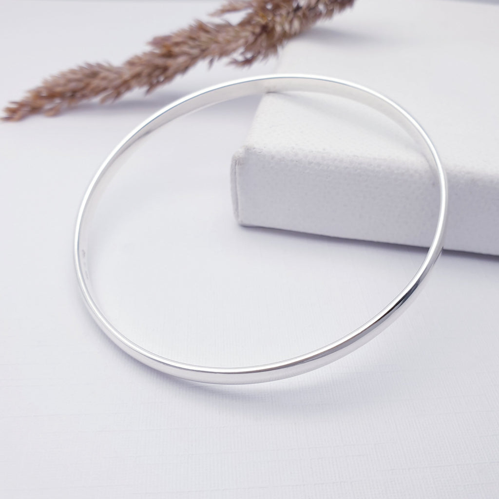 Sterling Silver D-shaped bangle on a white background, with filigree in the top left of the photo