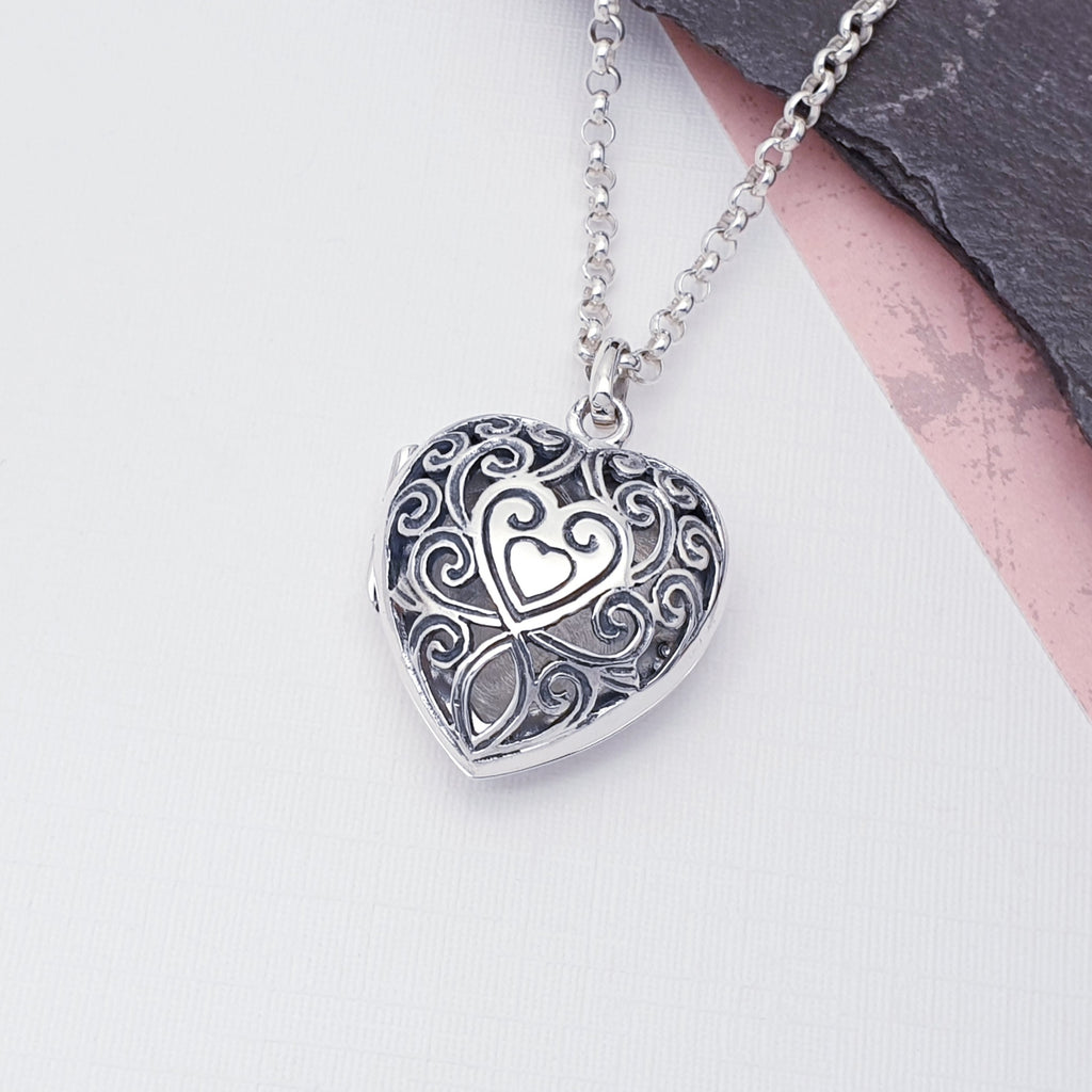 Sterling Silver Filigree Heart Locket on a white background with slate in the top right corner