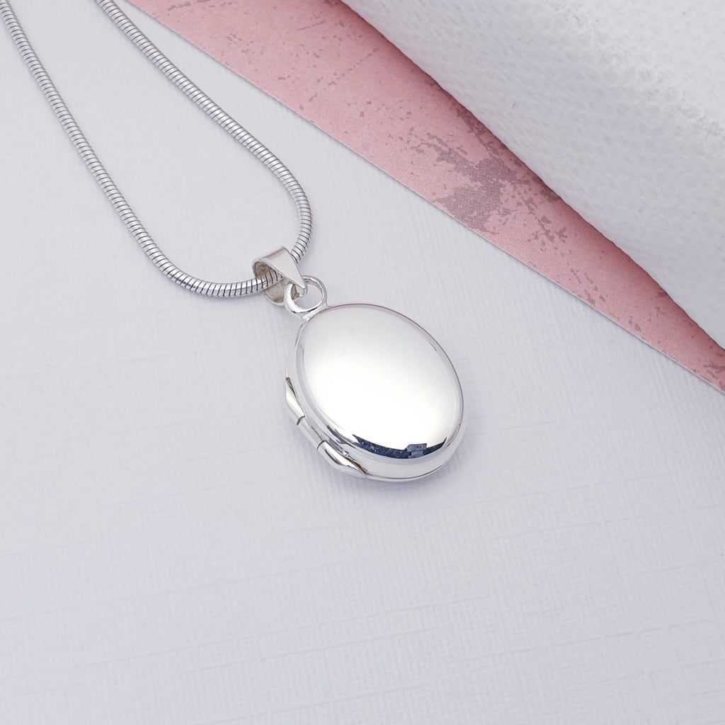 Sterling Silver Small Oval Locket on a white background with a small pink detail in the top right half of the image