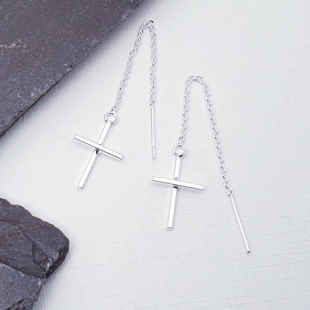 Our Cross pull through earrings displayed on a white background with slate on the left hand side as decoration