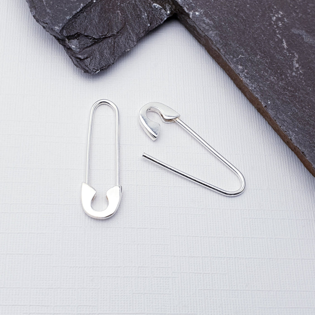 Our Sterling Silver Safety Pin Earrings displayed on a white background with slate on the top right hand corner as decoration
