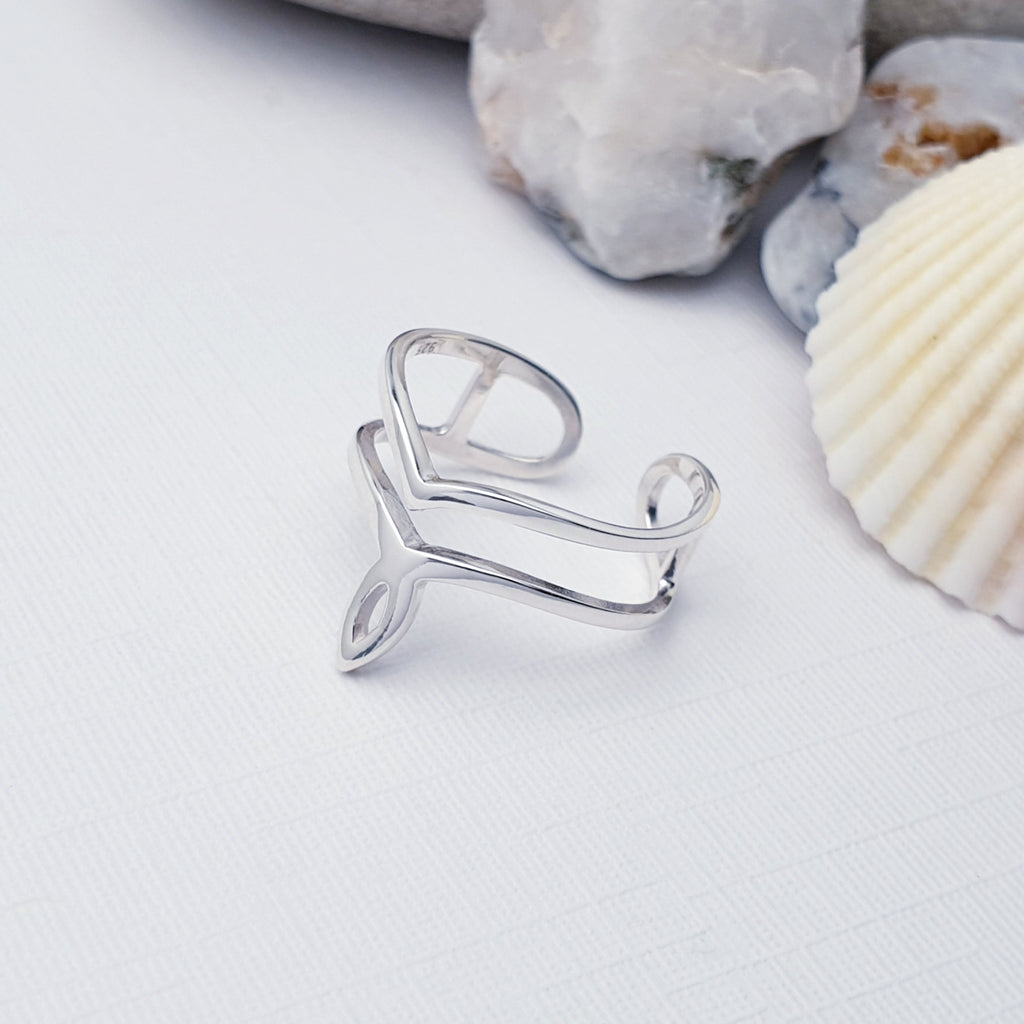 Our Sterling silver twin band toe ring displayed on a white background with stones and shells as decorations
