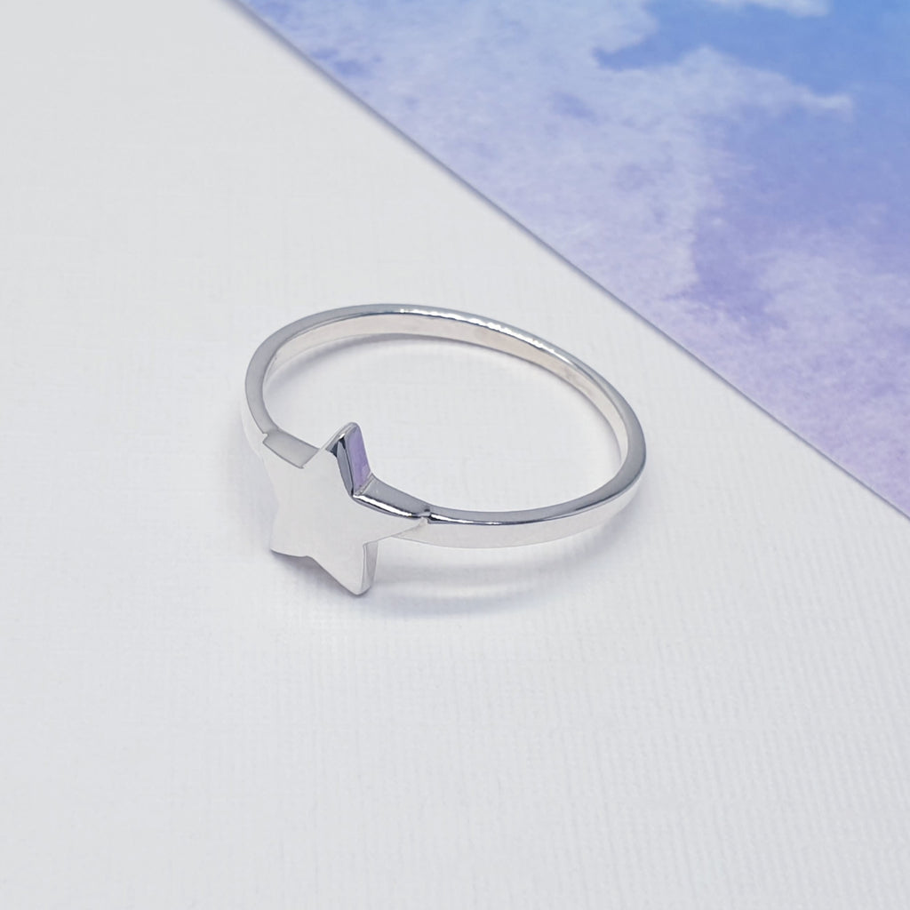 Our sterling silver star ring displayed against white with blue card in the background as decoration
