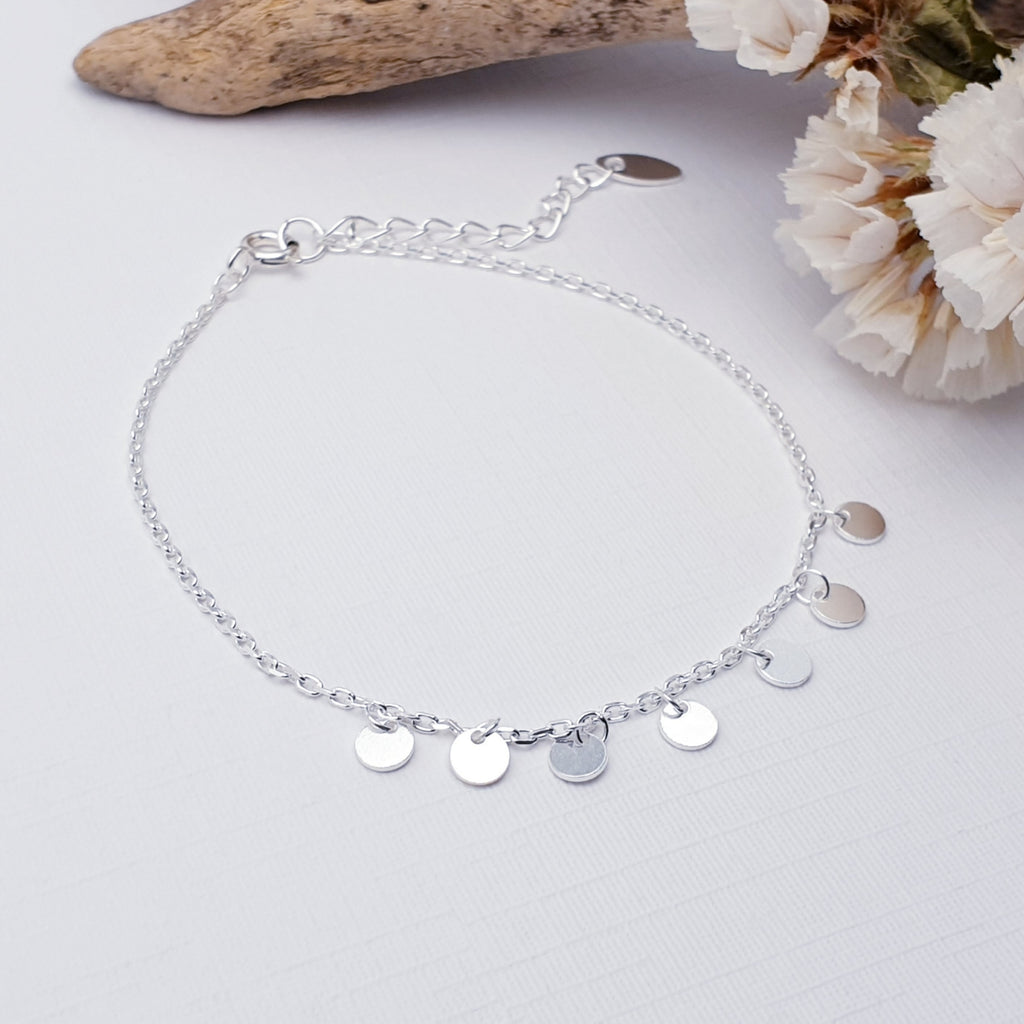 Our simple disc bracelet displayed against a white background with bark and flowers as decoration