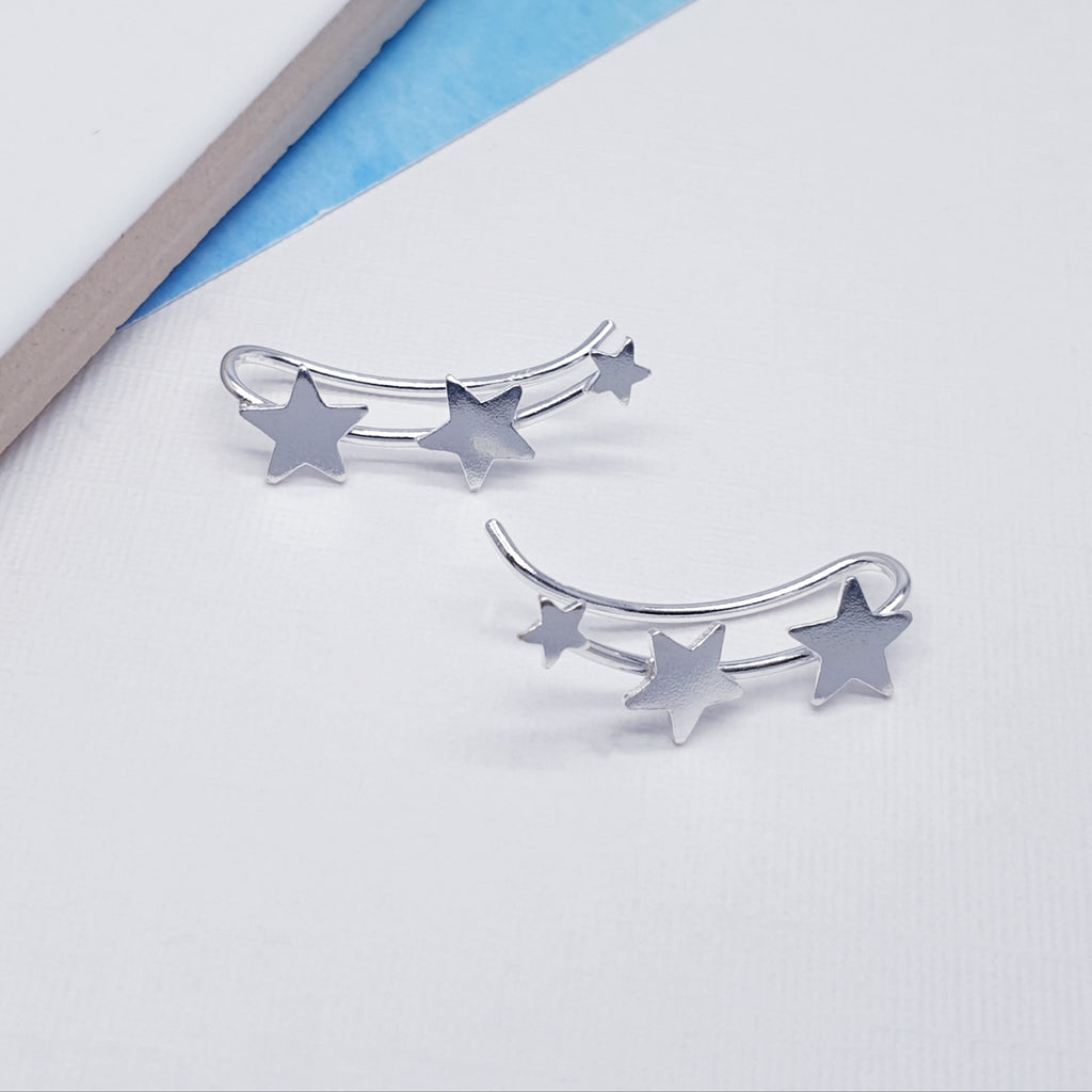 Silver star-shaped earrings on a light gray background