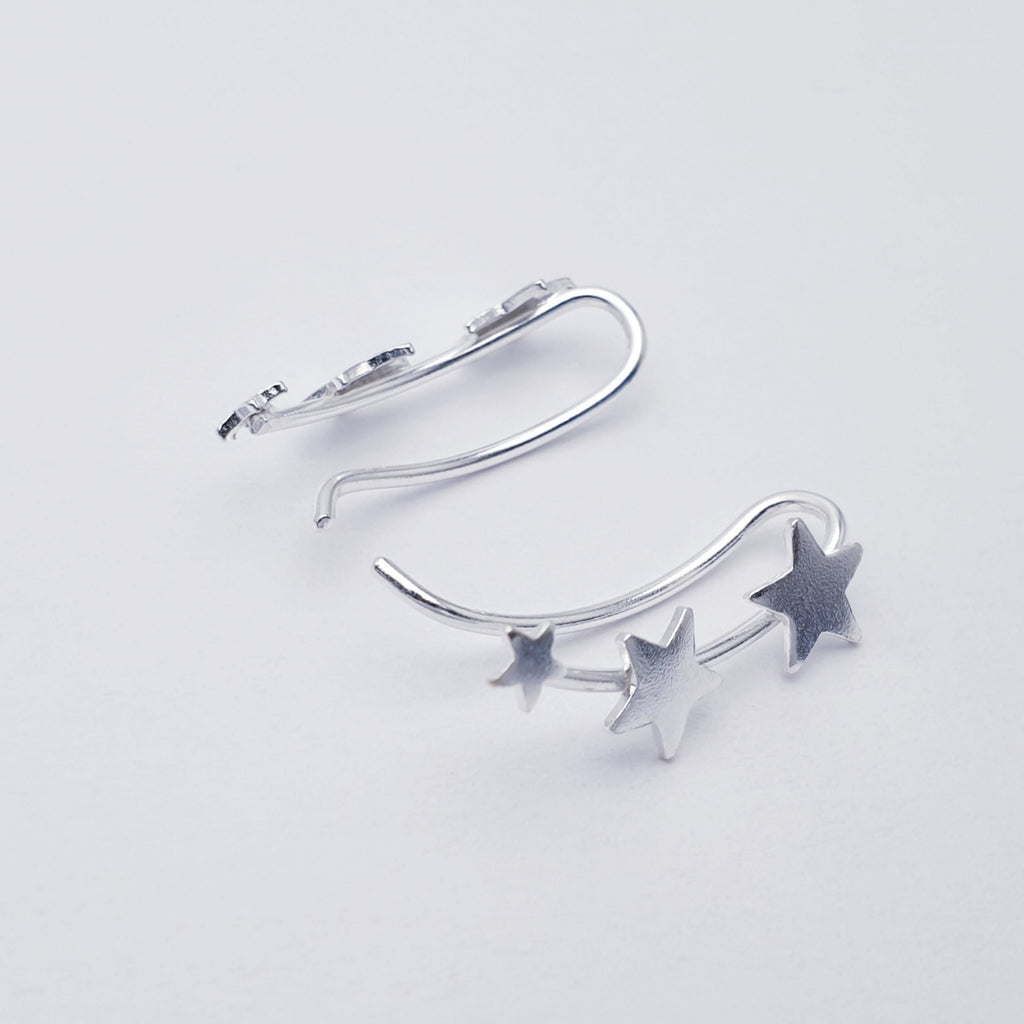Silver star-shaped earring on a light gray background