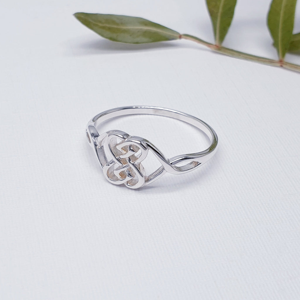 Our celtic knot ring against white with leaves in the bakground as decoration