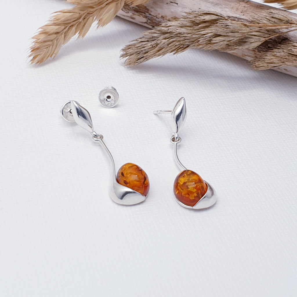 Our Toffee Amber Sterling Silver Ripple Earrings are perfect for everyday wear or special occasions.  Simple yet eye-catching, each earring features a oval shaped toffee amber stone held in Sterling Silver that curves elegantly up the stone. The stud back fastening means that these earrings are extra secure, so you don't have to worry about losing them.