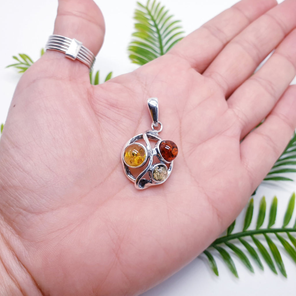 a Mixed Amber Sterling Silver pendant in the palm of a hand