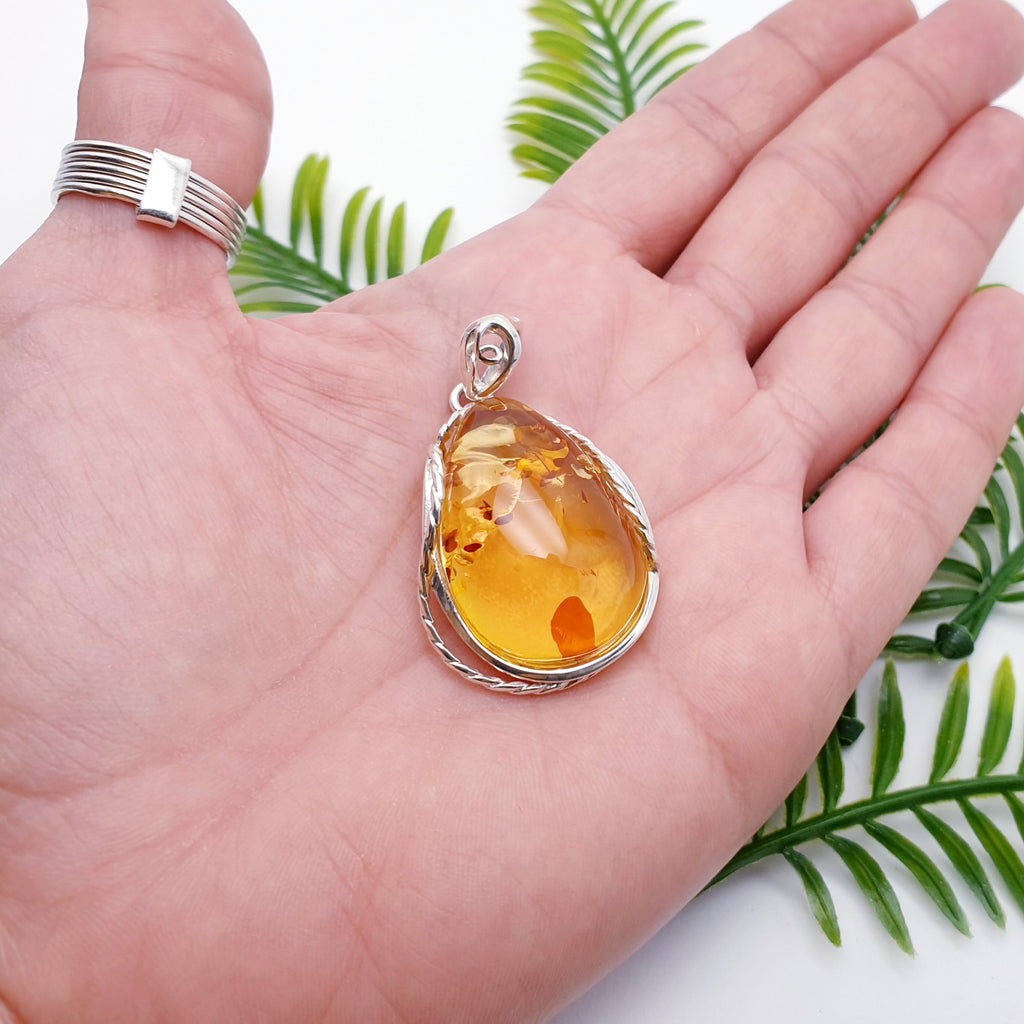 large toffee amber pendant placed in the palm of a hand.