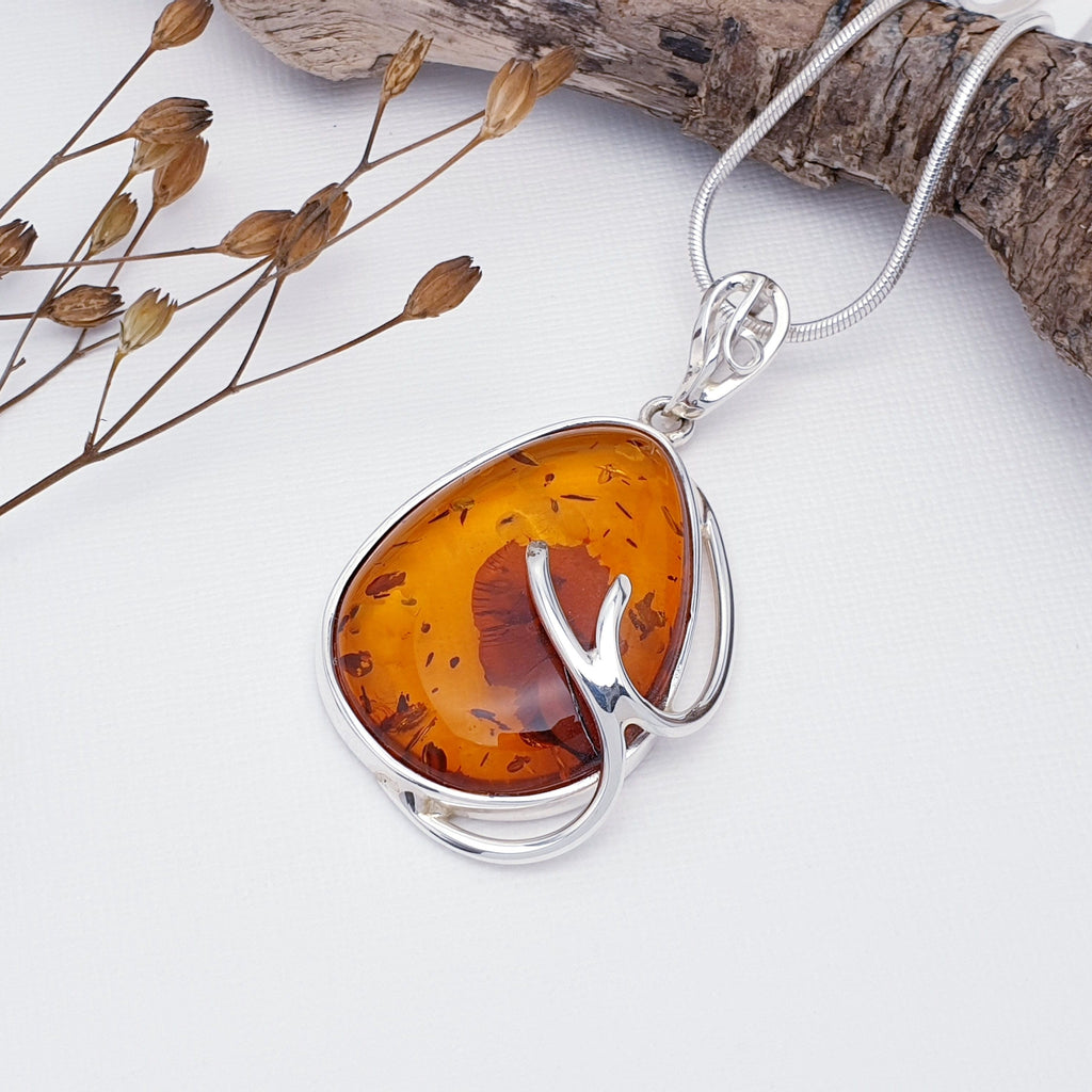 A large toffee amber pendant, with natural inclusions, set in sterling silver with branch detailing. With foliage decor