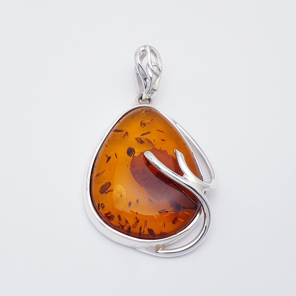 A large toffee amber pendant, with natural inclusions, set in sterling silver with branch detailing.