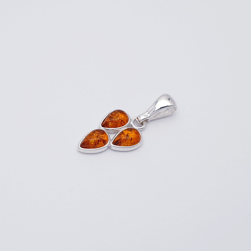 a toffee amber pendant with three teardrop shaped gemstones in a sterling silver setting