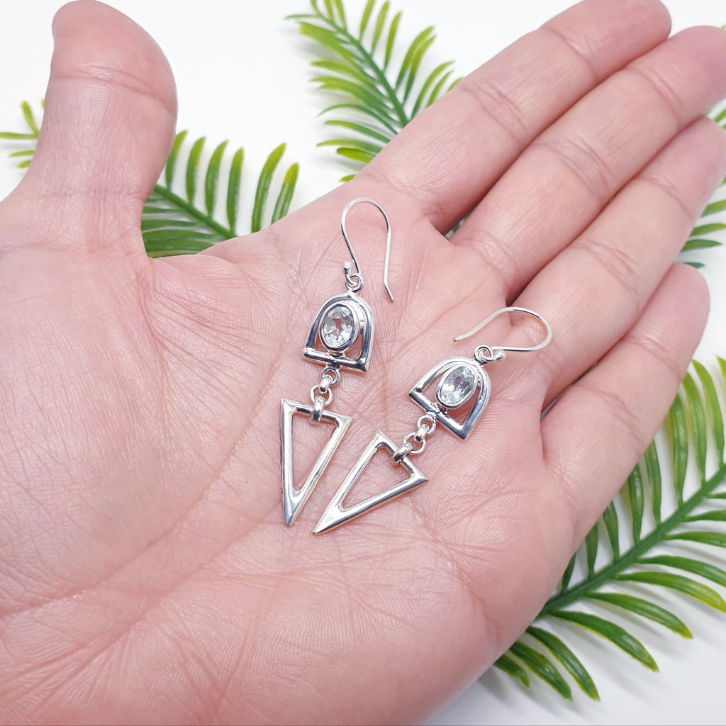 Blue topaz and sterling silver dangly drop triangular shape earrings in the palm of a hand