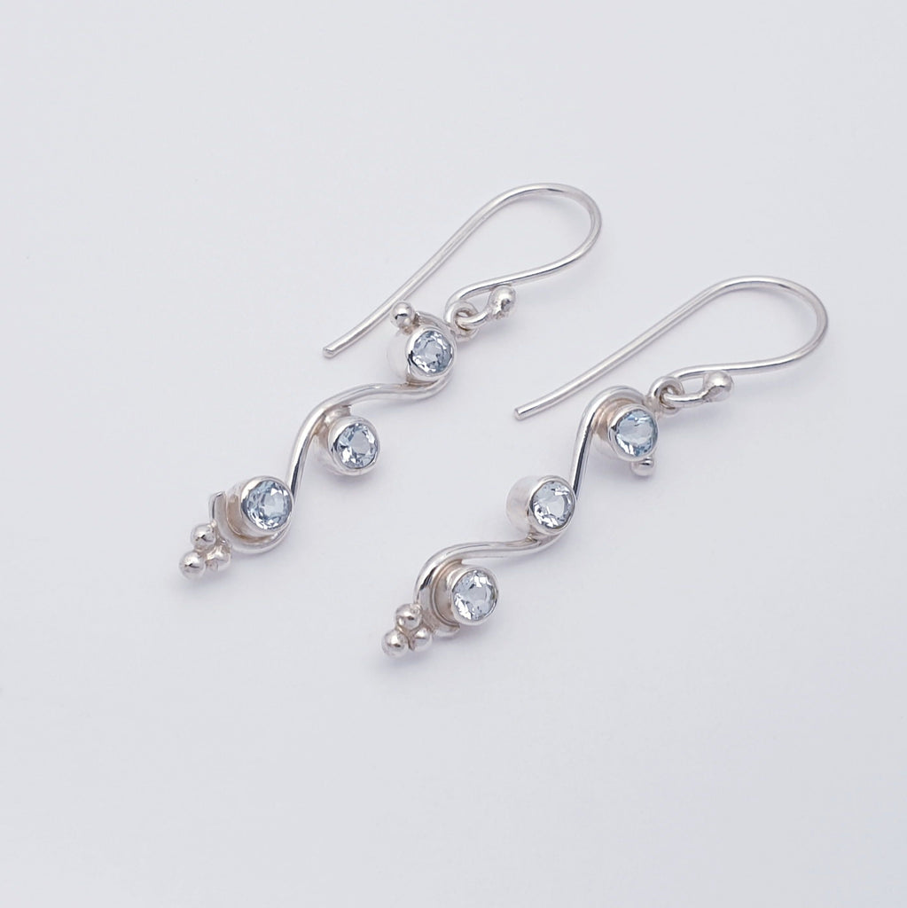 blue topaz gemstone and sterling silver swirly drop earrings flat lay