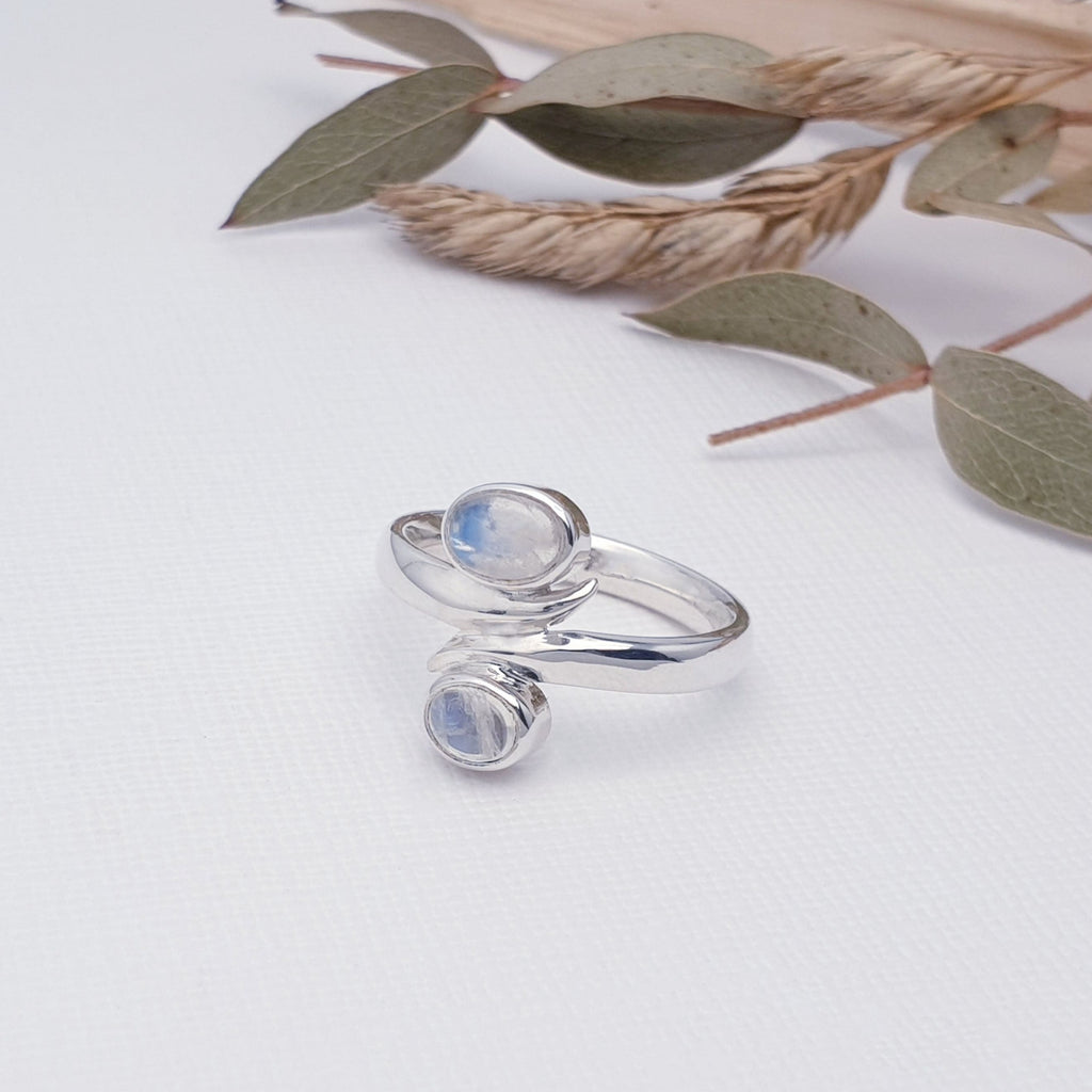 Double moonstone gemstone and sterling silver ring with earthy foliage behind