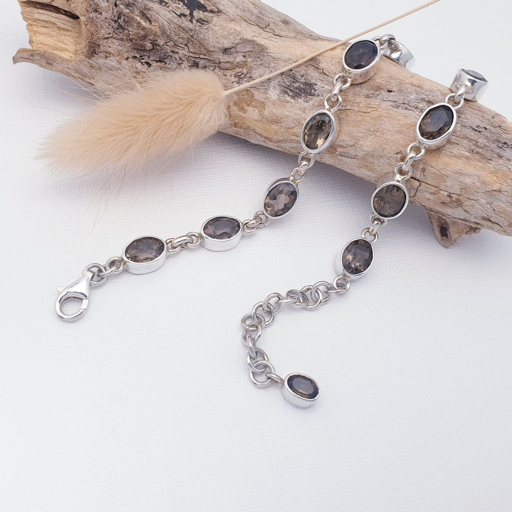An oval gemstone bead smoky quartz and sterling silver bracelet, draped over driftwood