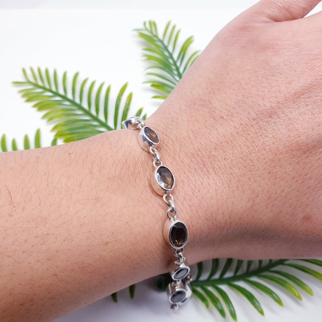 An oval gemstone bead smoky quartz and sterling silver bracelet on a models wrist